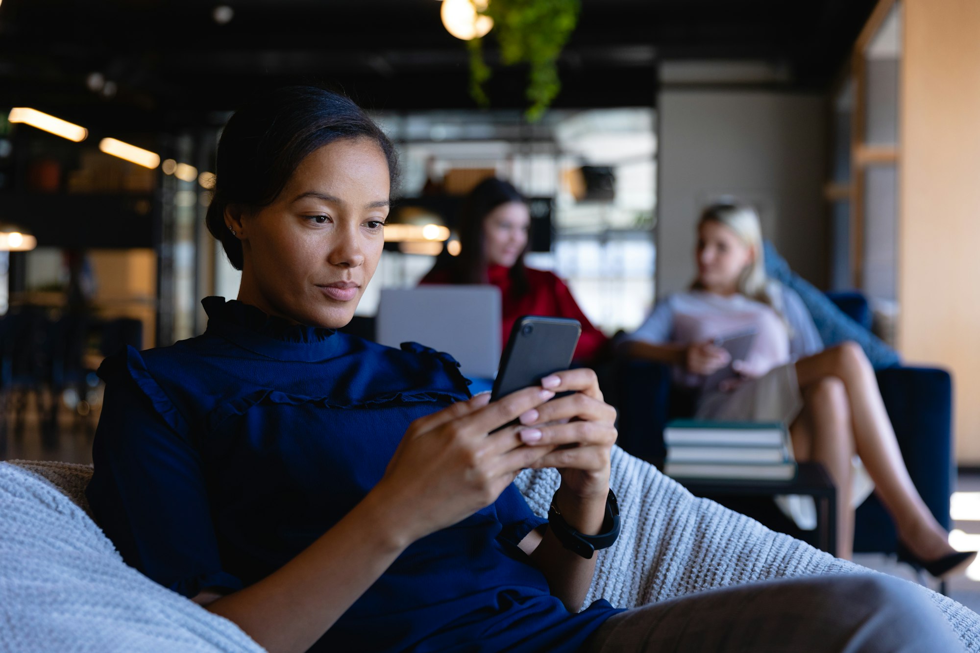 African American woman using her phone in modern office